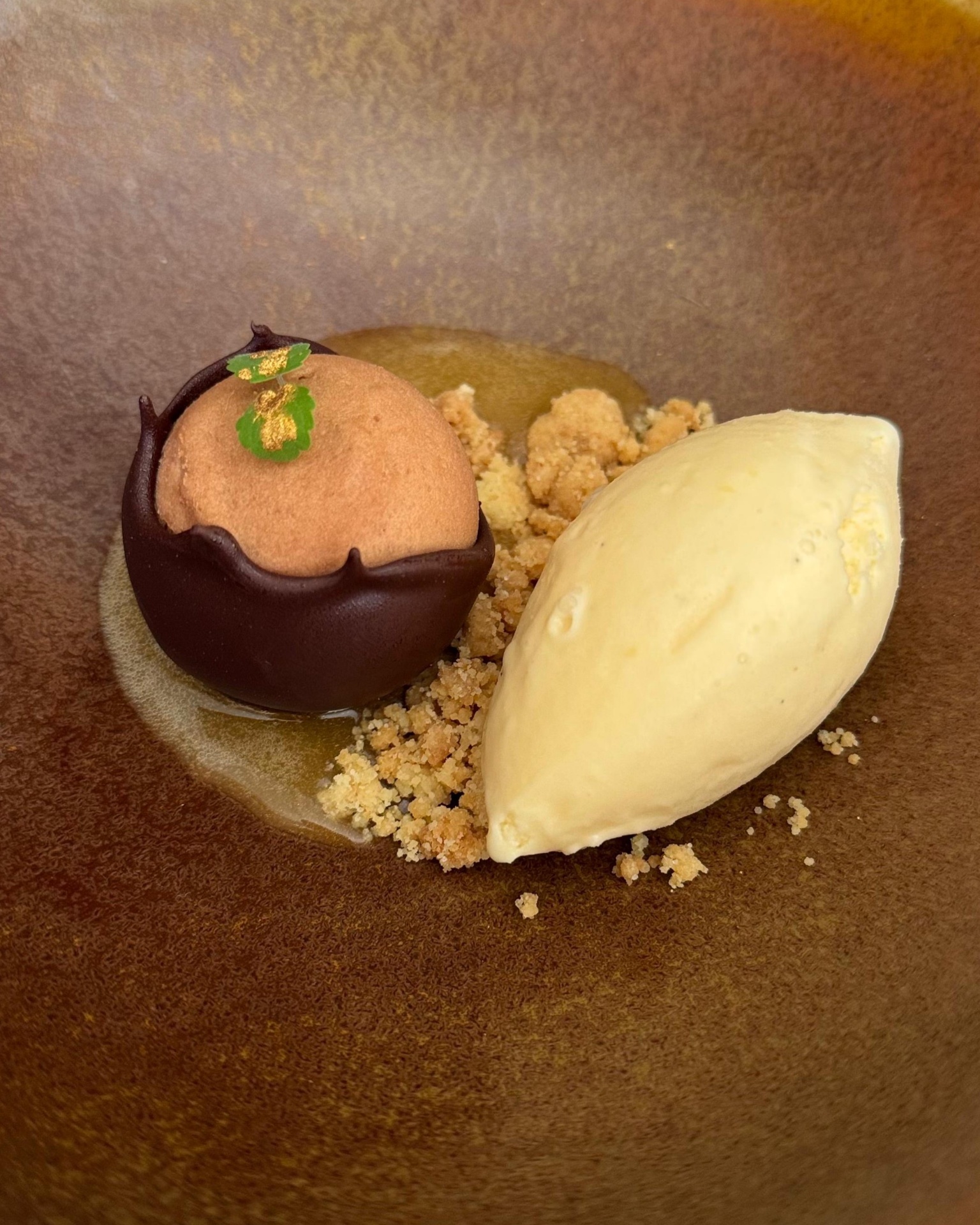 Mousse de chocolate relleno de praline cremoso, reduccionde anana, crumble, y helado de caramelo