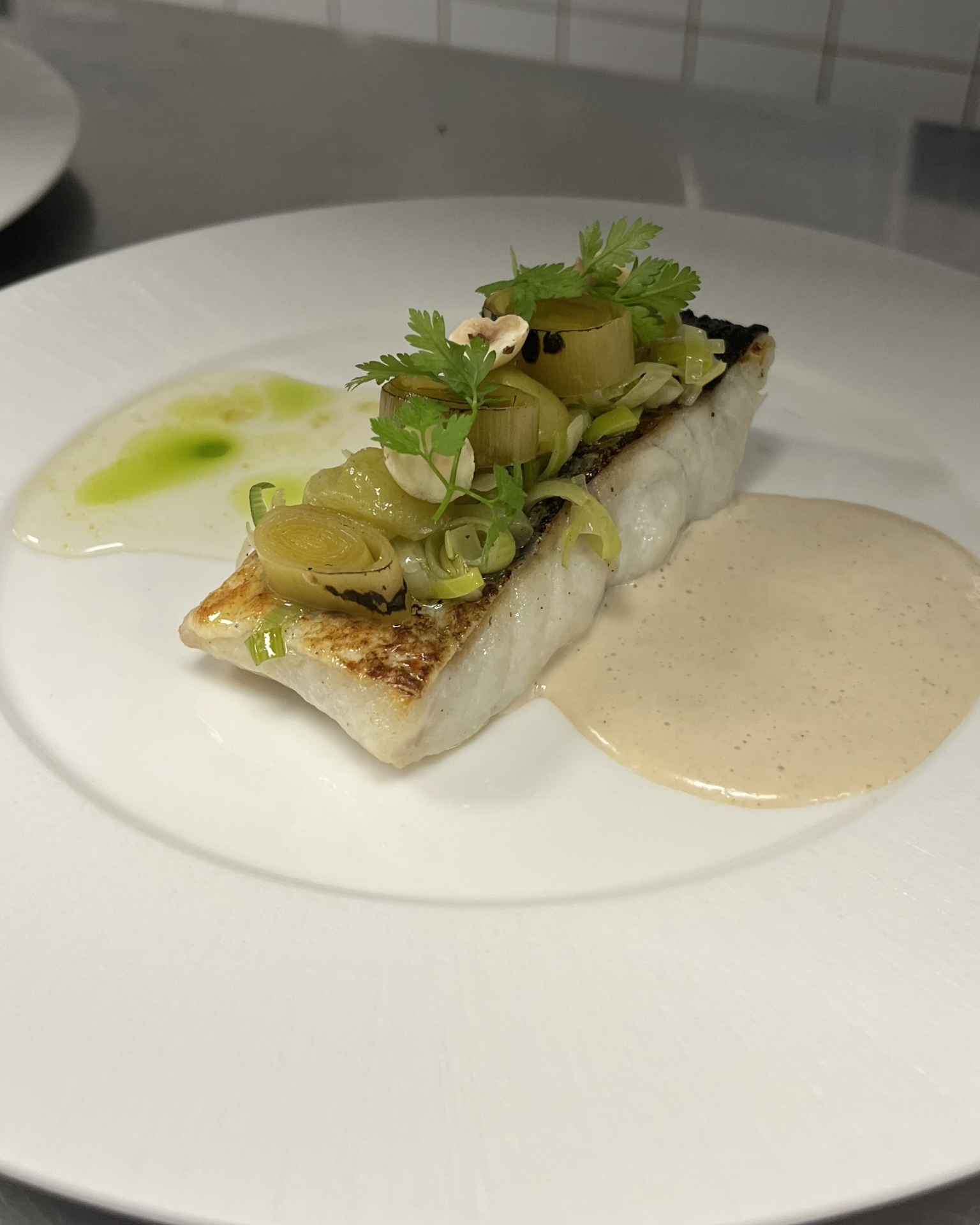 Abadejo asado, puerro salteado y en sousvide, uvas blancas asadas, avellanas, beurre blanc de tahini y reduccion de agraz